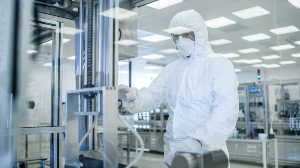 Technisch specialist in cleanroom-kleding werkt nauwkeurig aan geavanceerde apparatuur in een high tech productiefaciliteit.